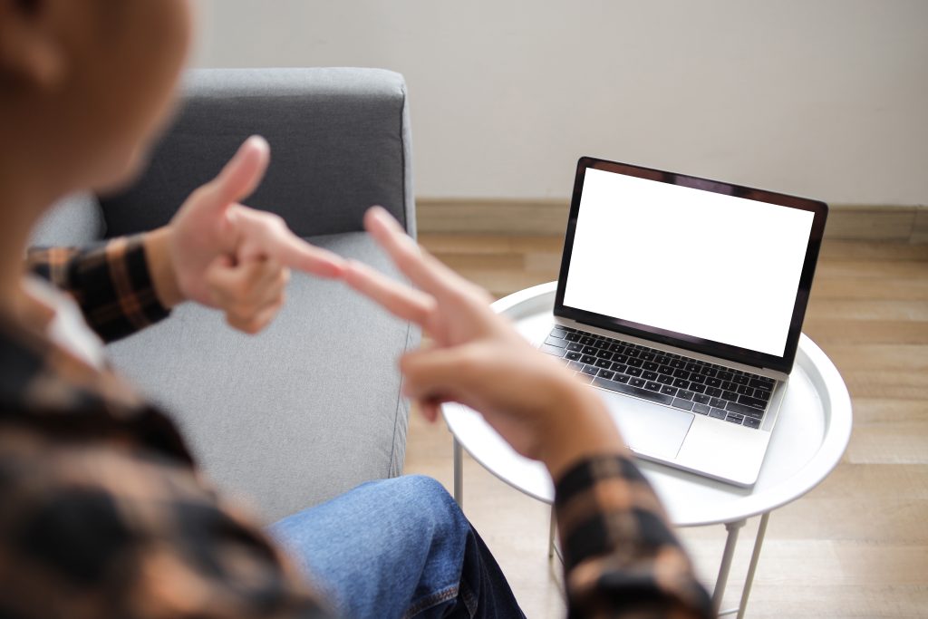 Person zeigt Gebärdensprache vor Laptop