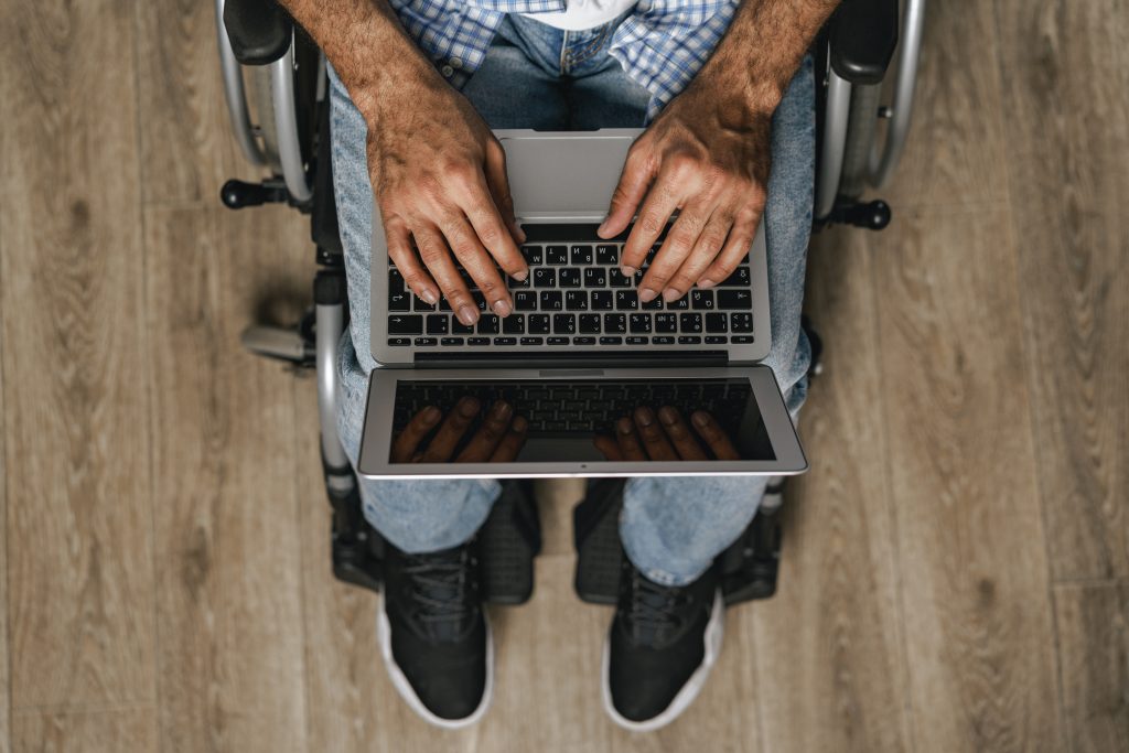 Mann im Rollstuhl mit Laptop am Schoß