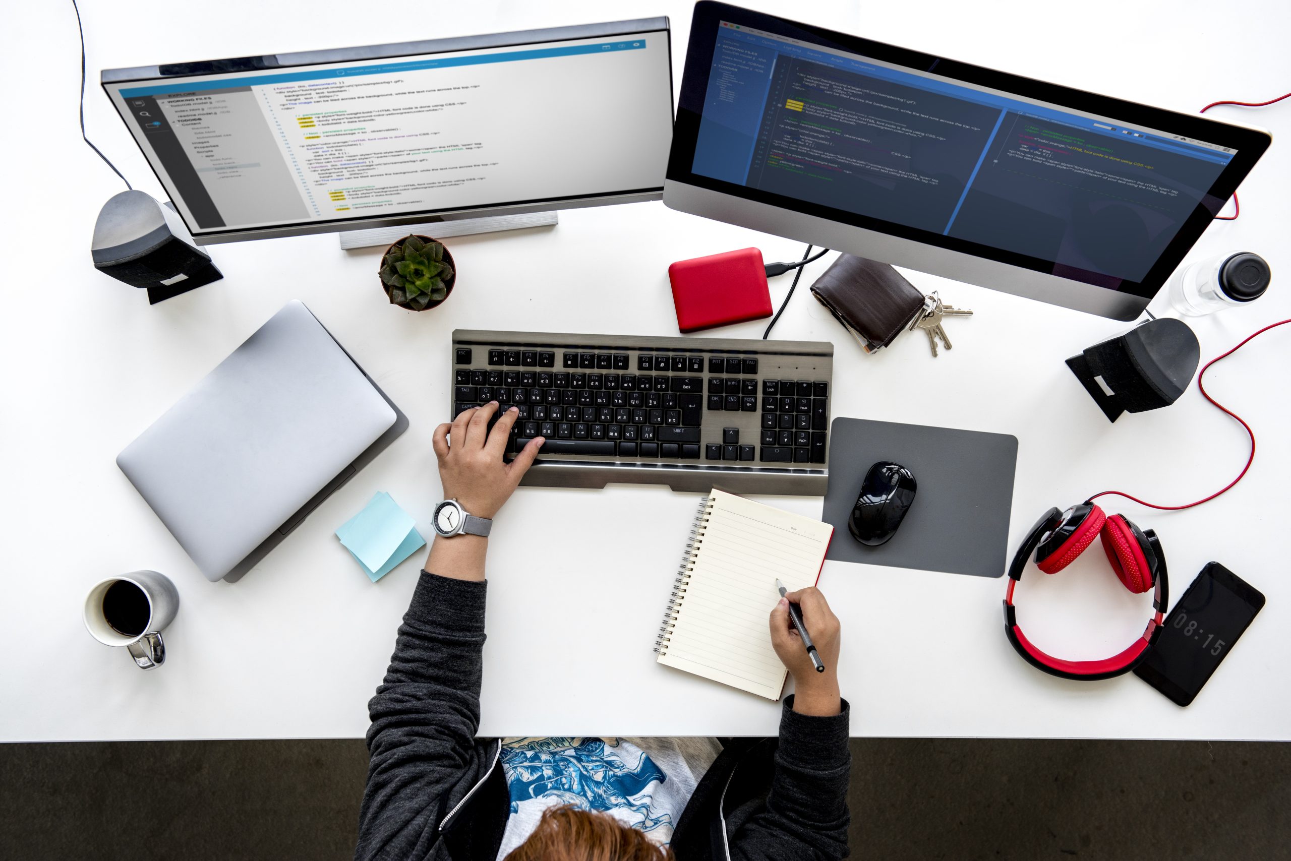 Mann sitzt am Schreibtisch mit zwei Laptops